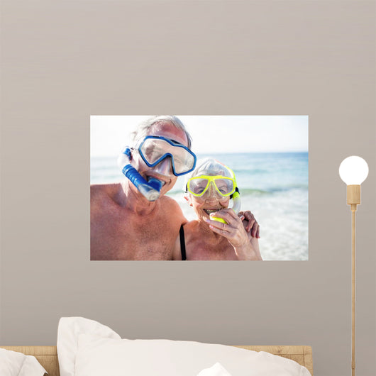 Happy senior couple with their diving mask at beach Wall Mural