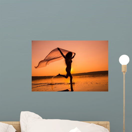 Silhouette of girl running on the beach Wall Mural