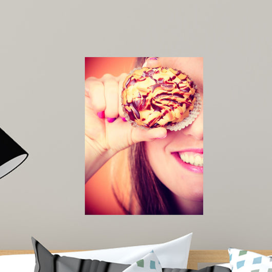 Funny woman holds cake in hand covering her eye Wall Mural