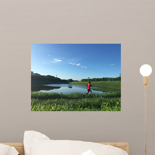 Male runner on path around lake Wall Mural