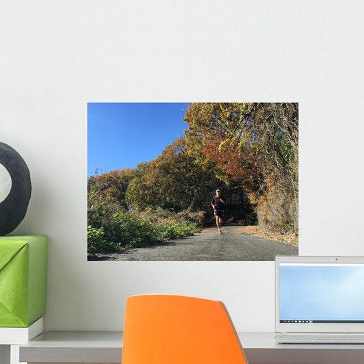 Man running on country road with autumn leaves Wall Mural