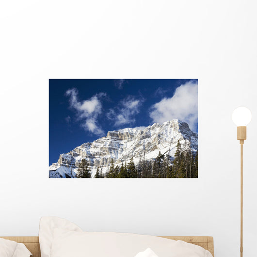 Snow covered mountain peak, blue sky, clouds Wall Mural