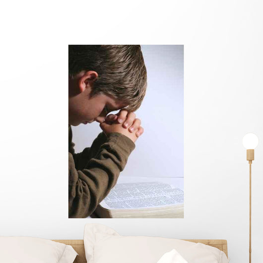 young boy praying over his bible Wall Mural