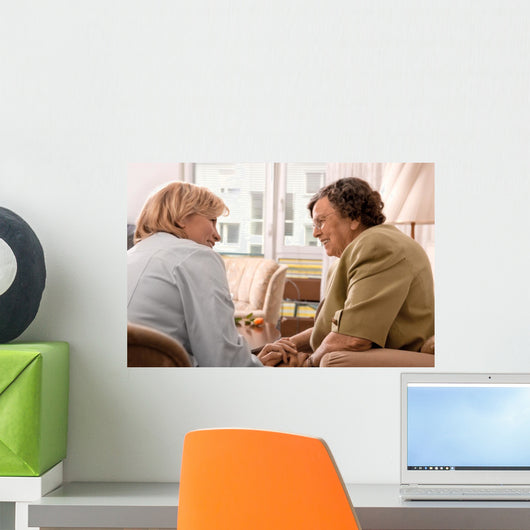 Senior woman is visited by her doctor or caregiver at home Wall Mural