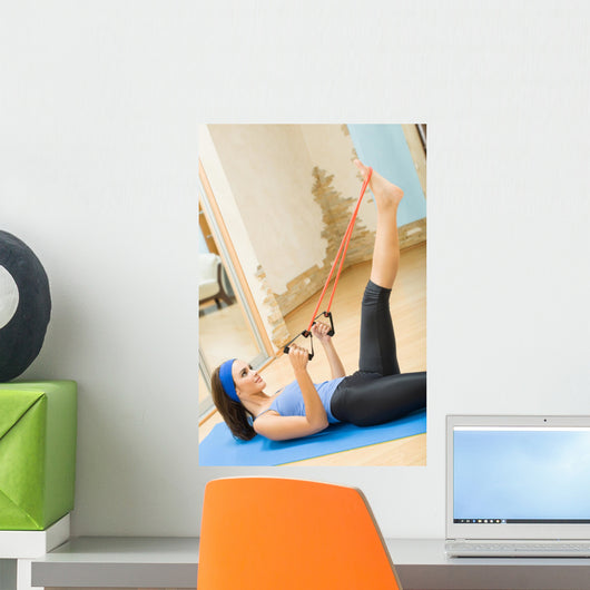 Young happy woman exercising with expander at home Wall Mural