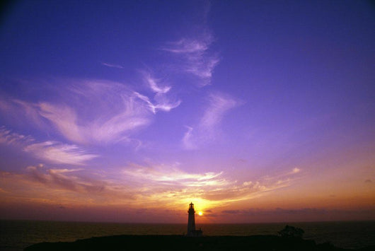 Luminous Sky Behind Distant Lighthouse Wall Mural