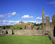 Old Ruins Of An Abbey With A Castle In The Background Wall Mural