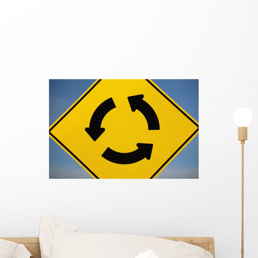 A Yellow Sign Showing Three Arrows Going In A Circle Wall Mural