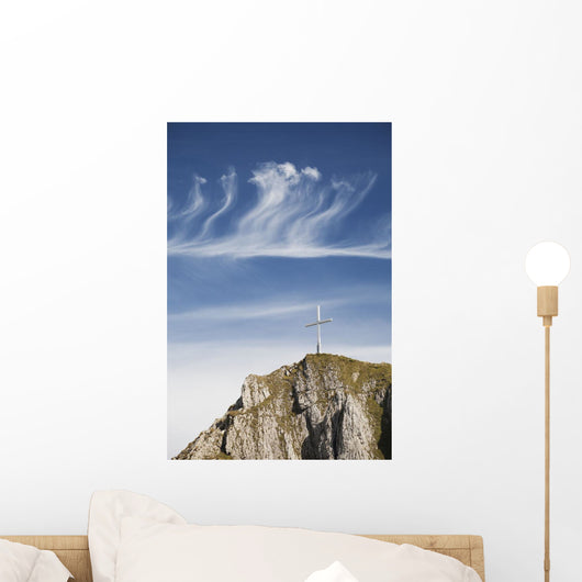 Mountain Peak With A Cross On Top Against A Blue Sky With Clouds Wall Mural