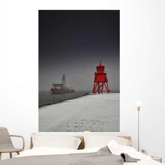 A Red Lighthouse Along The Coast In Winter With A Boat Off The Shore Wall Mural