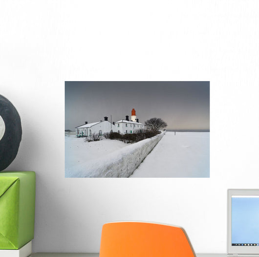 A Snow Covered Fence With A Lighthouse And Building In The Background Wall Mural