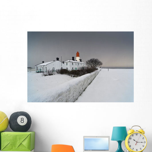 A Snow Covered Fence With A Lighthouse And Building In The Background Wall Mural