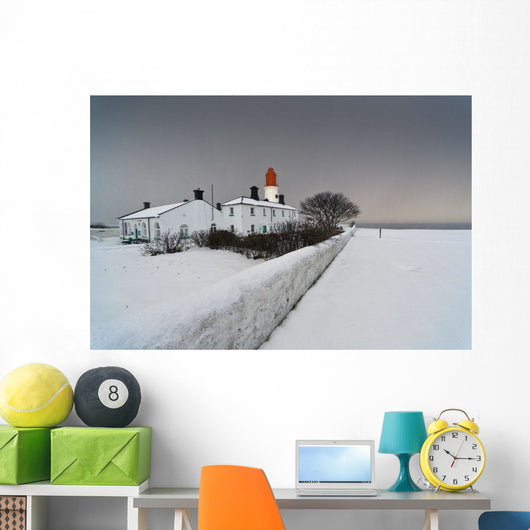 A Snow Covered Fence With A Lighthouse And Building In The Background Wall Mural