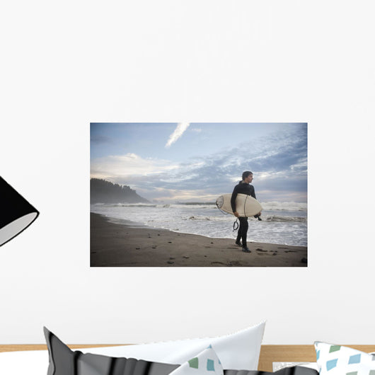 A Young Man Carries His Surfboard Down The Beach Wall Mural