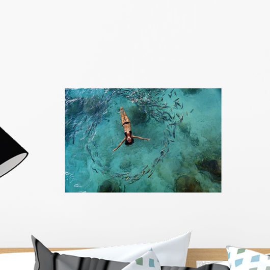 School Of Fish Encircling Woman Floating In Tropical Ocean Water Wall Mural