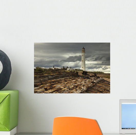 A Lighthouse And Piles Of Logs On The Shore Wall Mural