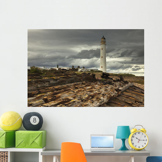 A Lighthouse And Piles Of Logs On The Shore Wall Mural