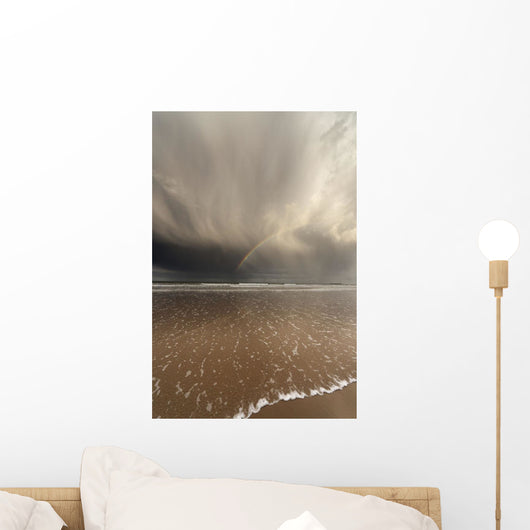 Tide Coming Up Onto The Beach With A Rainbow In The Clouds Wall Mural