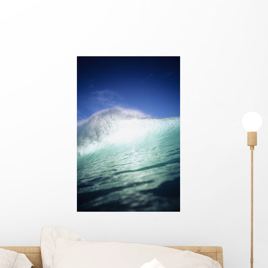 Closeup angle of green wave with backlit crest, bright blue sky Wall Mural