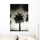 Silhouetted palm tree centered between other palm tree tops at dusk Wall Mural