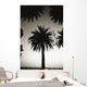 Silhouetted palm tree centered between other palm tree tops at dusk Wall Mural
