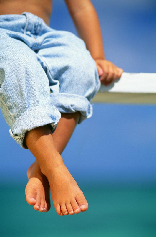 Hawaii, Legs And Feet Of Young Boy Sitting On A Bench By The Ocean Wall Mural