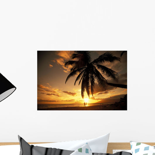 Distant View Of Couple Walking Along Beach At Sunset Wall Mural