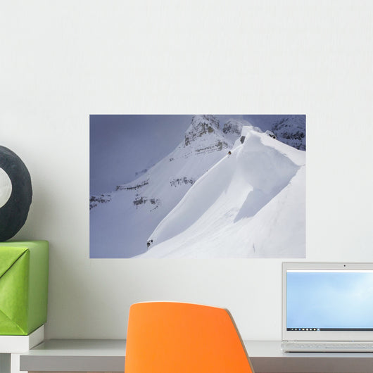 Skier On Crest Of Big Drop, Dwarfed By Mountain Wall Mural