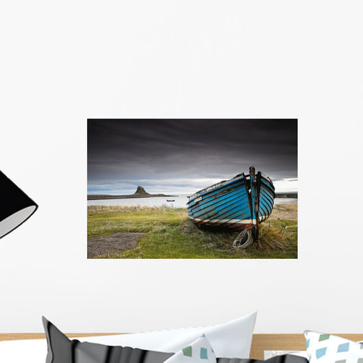 A Weathered Boat Sitting On The Shore With Lindisfarne Castle Wall Mural