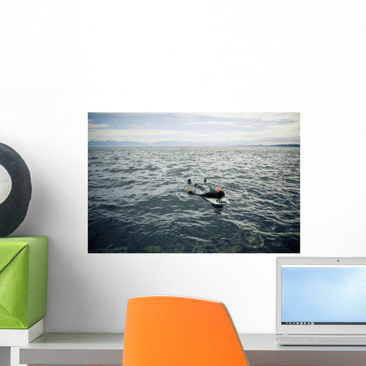 A Surfer Lays On His Back On His Surfboard In The Water Wall Mural