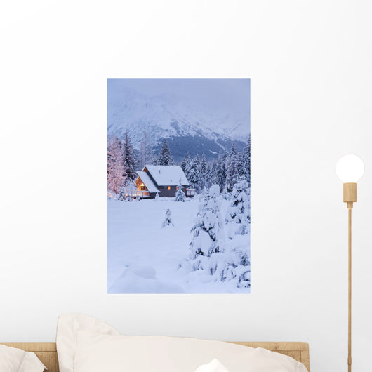 Snowcovered Home In A Wintry Meadow At Dawn With Inside Lights On Wall Mural