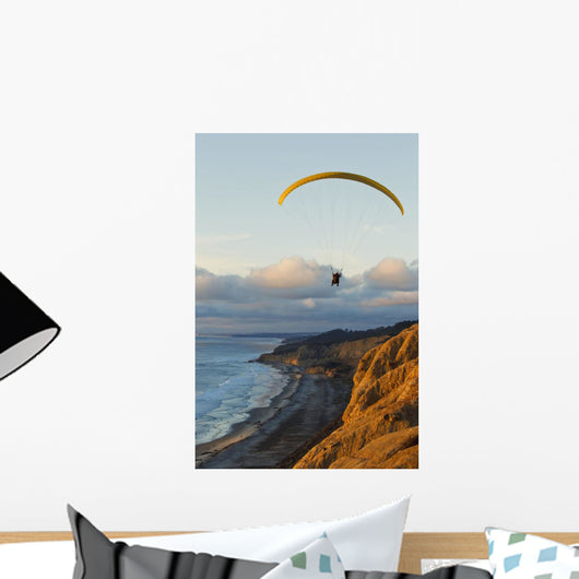 Paraglider flying over ocean cliffs at sunset EDITORIAL USE ONLY Wall Mural
