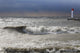 Storm waves crashing on a beach near a lighthouse on lake ontario Wall Mural