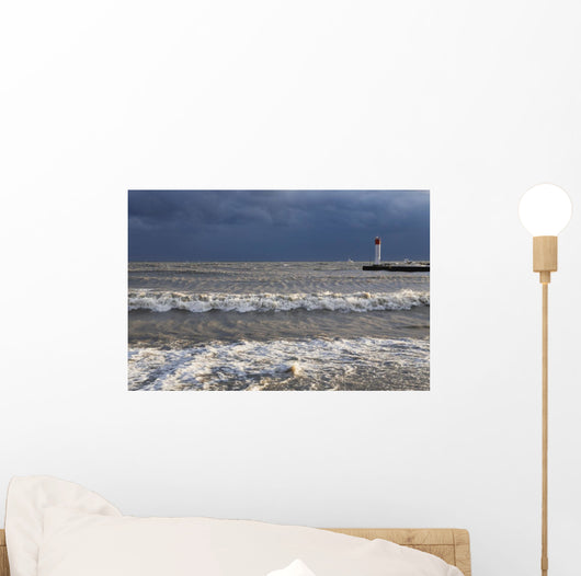 Storm waves crashing on a beach near a lighthouse on lake ontario Wall Mural