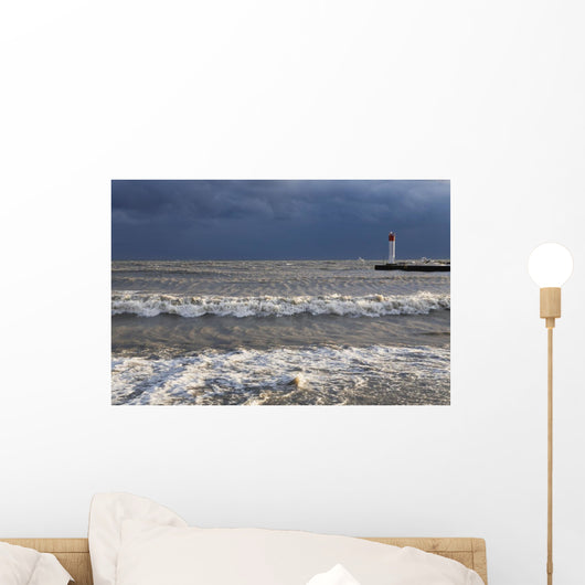 Storm waves crashing on a beach near a lighthouse on lake ontario Wall Mural
