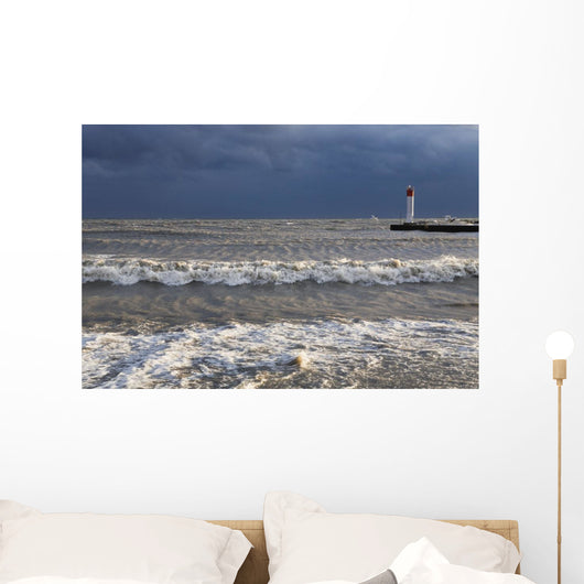 Storm waves crashing on a beach near a lighthouse on lake ontario Wall Mural