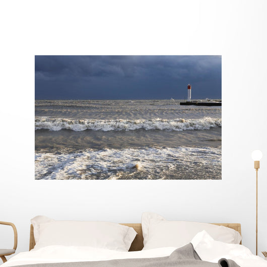 Storm waves crashing on a beach near a lighthouse on lake ontario Wall Mural