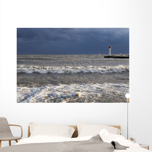 Storm waves crashing on a beach near a lighthouse on lake ontario Wall Mural