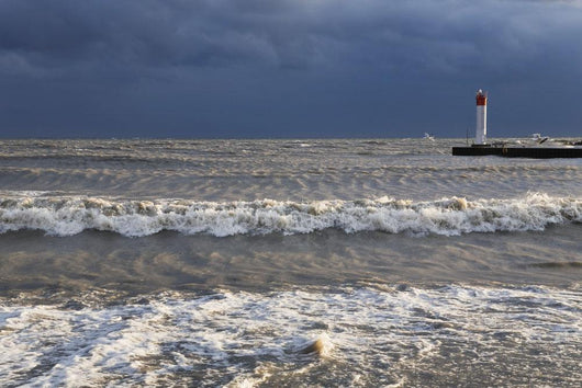 Storm waves crashing on a beach near a lighthouse on lake ontario Wall Mural