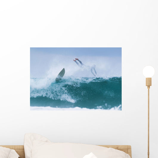 Surfer diving into water off his surfboard Wall Mural