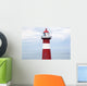 Red and white lighthouse along the coast with a sailboat Wall Mural