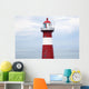 Red and white lighthouse along the coast with a sailboat Wall Mural