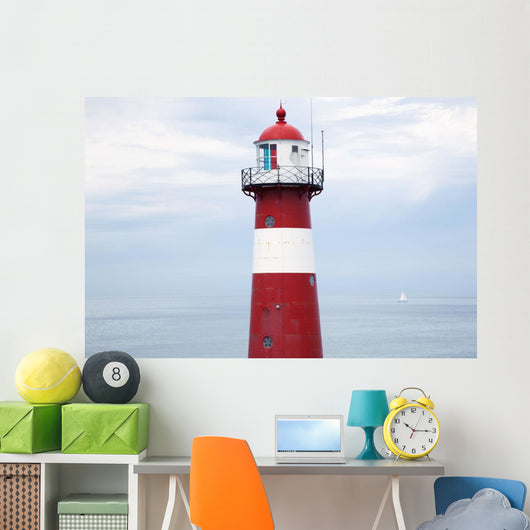 Red and white lighthouse along the coast with a sailboat Wall Mural