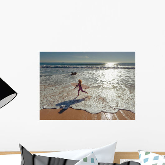 Woman in wetsuit running on beach Wall Mural