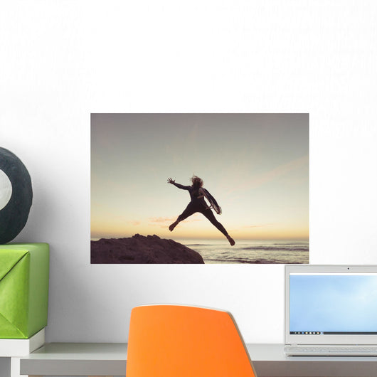 Spain, Andalusia, Cadiz, Costa de la Luz, Surfer jumping from rock Wall Mural