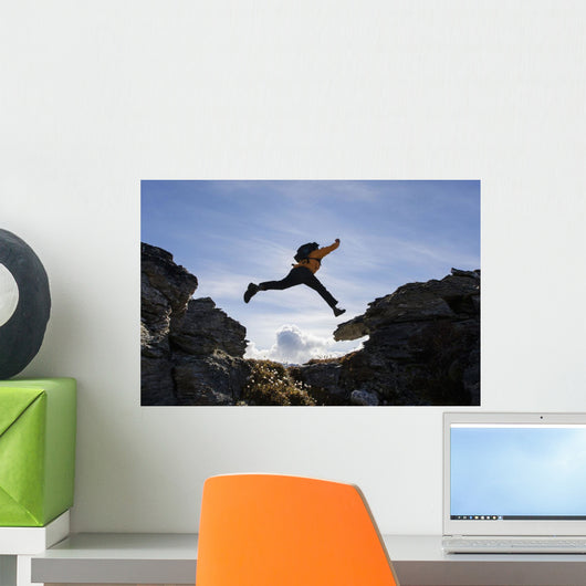 Hiker Leaps Between Rocks Near Noatak River In The Brooks Range Wall Mural