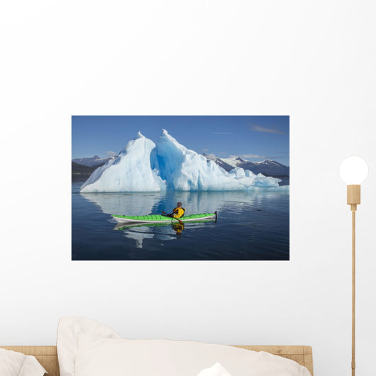 A Sea Kayaker Paddles Beside An Iceberg Wall Mural