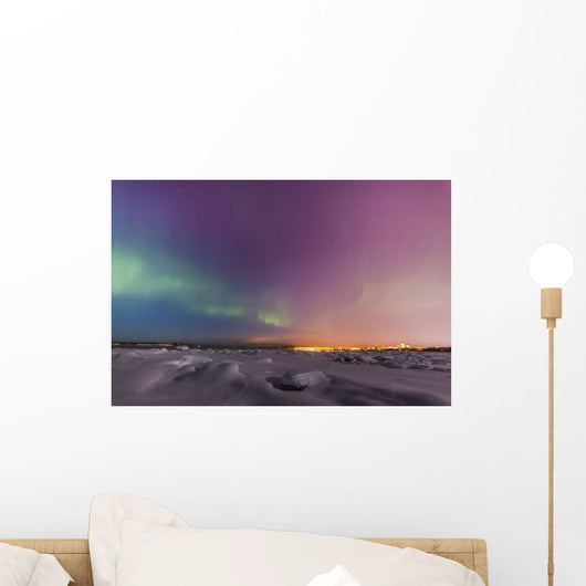 Northern lights shine above city skyline in this nighttime view Wall Mural