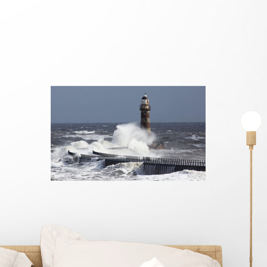 Waves crashing into a lighthouse Wall Mural