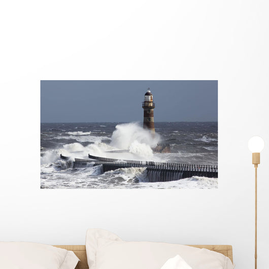 Waves crashing into a lighthouse Wall Mural